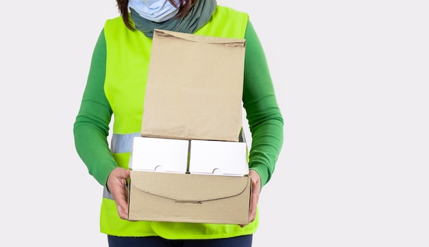 노동자는 종이 상자, 배달 개념을 많이 들고 녹색 조끼에 있습니다.
