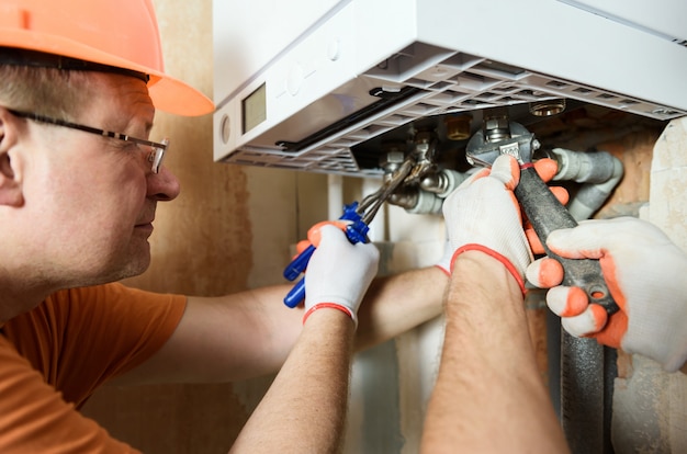 The worker is installing the gas boiler pipes.