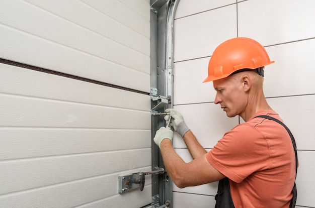 Il lavoratore sta installando i cancelli dell'ascensore nel garage.