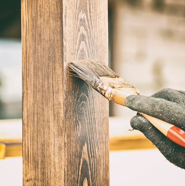 The worker is painting the wooden terrace