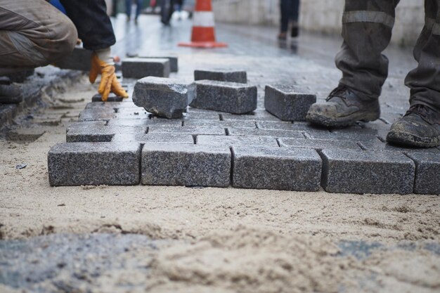 A worker laying concrete bricks on each other for building a new sidewalk