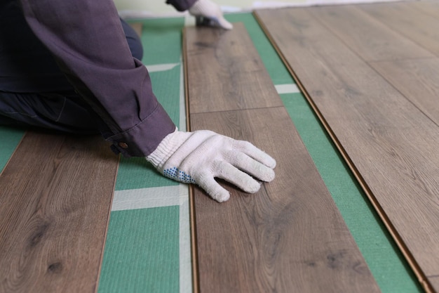 Worker lays the laminate in the apartment laminate is lying on the floor in the apartment the master...