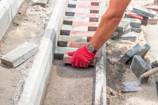 A worker lays paving slabs on a staircase in a park