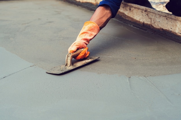 worker leveling concrete pavement for mix cement at construction site