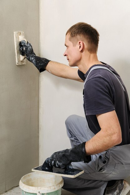 Worker makes final smoothing plaster on the wall.