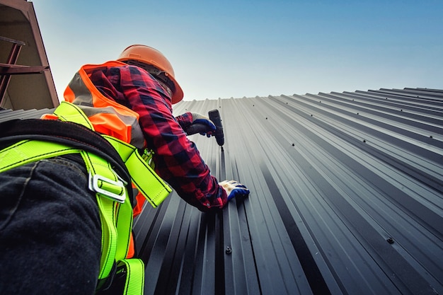 安全ヘルメット付きの家の屋根に商人を建てる労働者の男