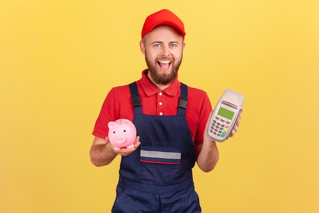 Worker man holding pos payment terminal and piggy bank cashback using paypass for service payment