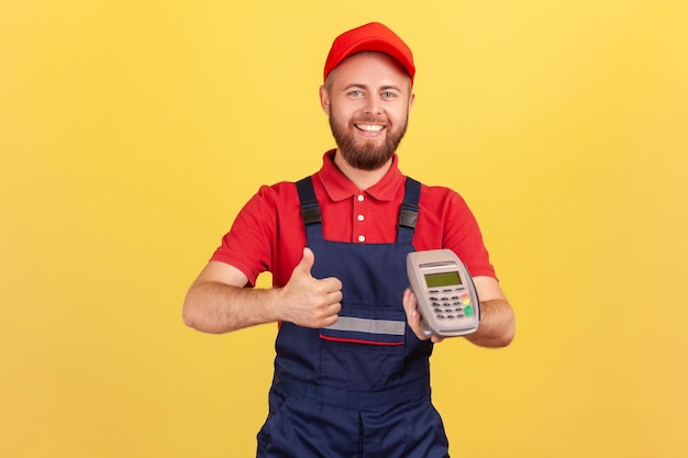 Worker man holding pos payment terminal using paypass for purchases payment showing thumb up