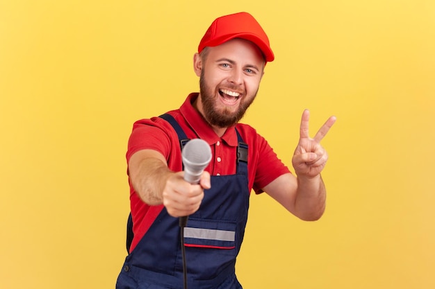 Uomo lavoratore che offre microfono per rispondere alle domande e mostrare il segno v