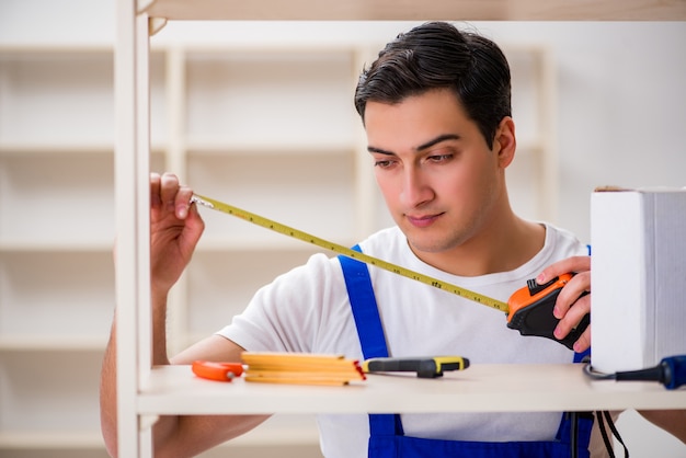 Uomo del lavoratore che ripara lo scaffale per libri di montaggio