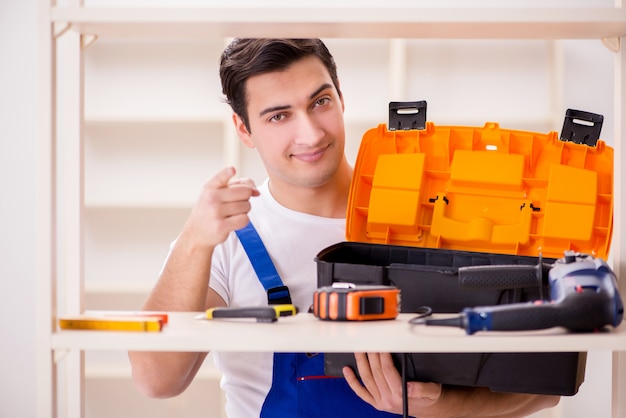 Uomo del lavoratore che ripara lo scaffale per libri di montaggio