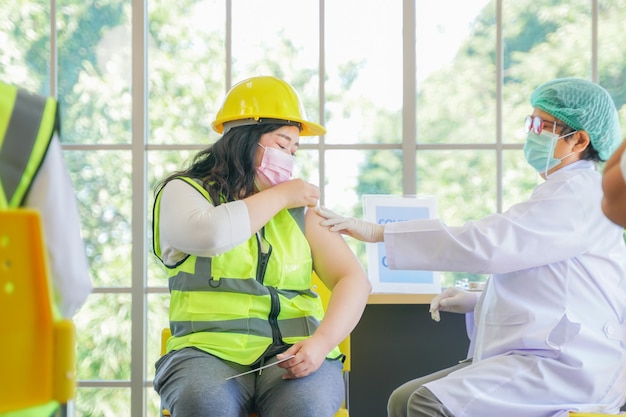 Worker man sitting to getting covid vaccine with nurse injecting vaccine to get immunity