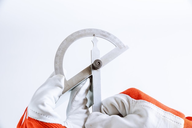 The worker measures the angle on the metal product with a digital protractor