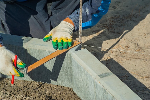 A worker measures a concrete block with a ruler closeup