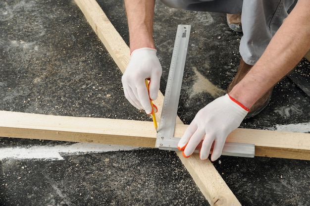 Worker measures off a wooden beam.