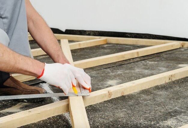 Worker measures off a wooden beam.