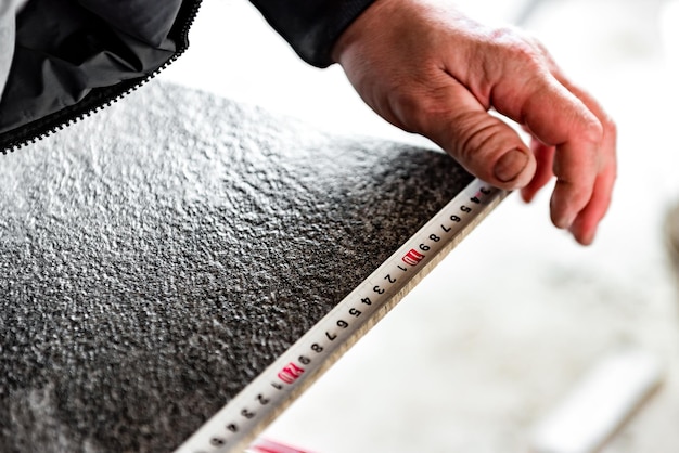 Worker measuring tile for cutting on tile cutter machine.