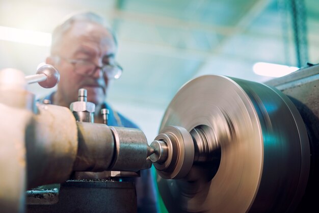 Worker operating industrial machine in metal workshop