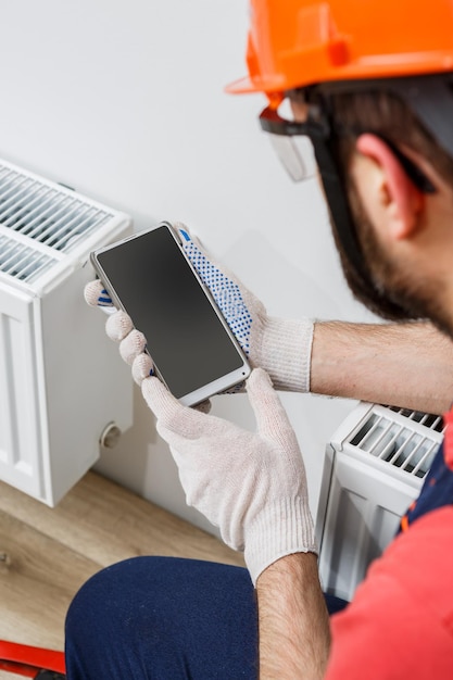 Un lavoratore con un casco arancione installa i radiatori in casa