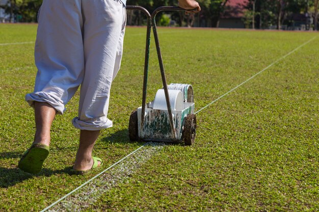 worker painting line on soccer, football, field