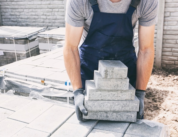 The worker picked up the stack with paving stones