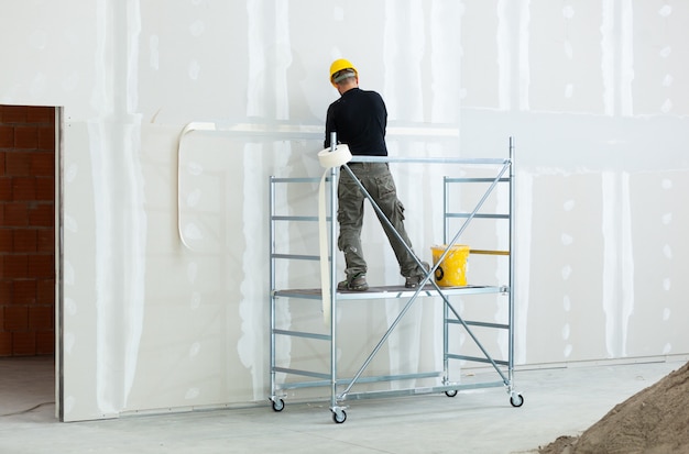 worker plastering gypsum board wall.