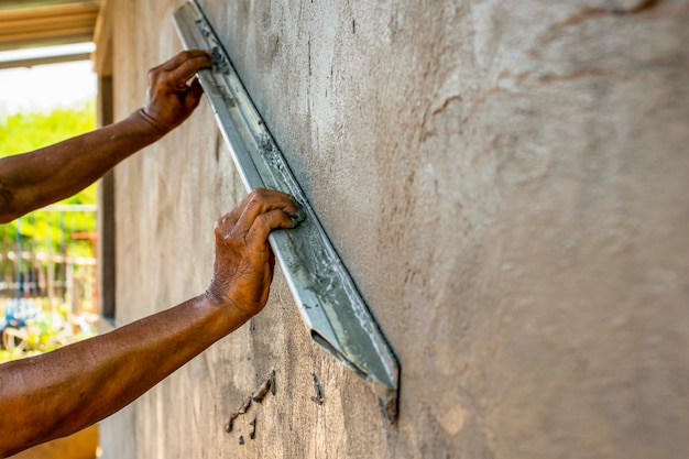 рабочий оштукатуривает стены для строительства домов