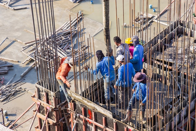 건설 현장에서 기초와 기둥 formwork 영역으로 쏟아지는 시멘트를 붓는 작업자.