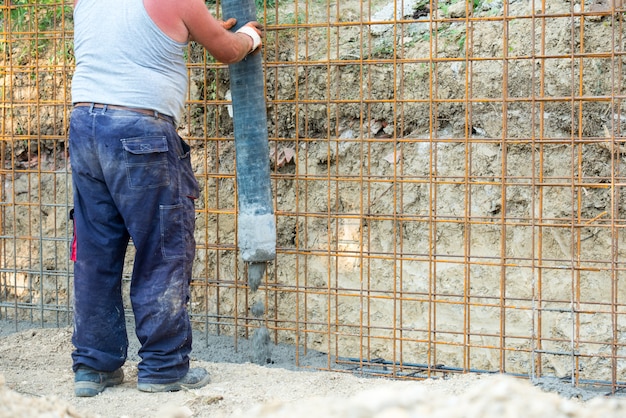 Worker pouring concrete mix at home foundation 