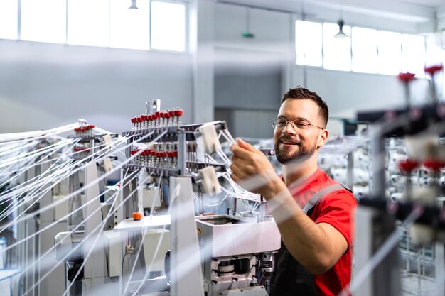 Worker preparing industrial knitting machine for work in textile factory