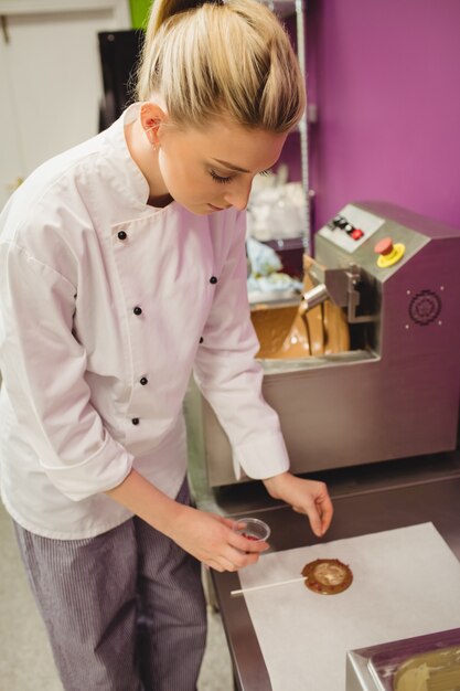 Worker preparing lollipop on wax paper