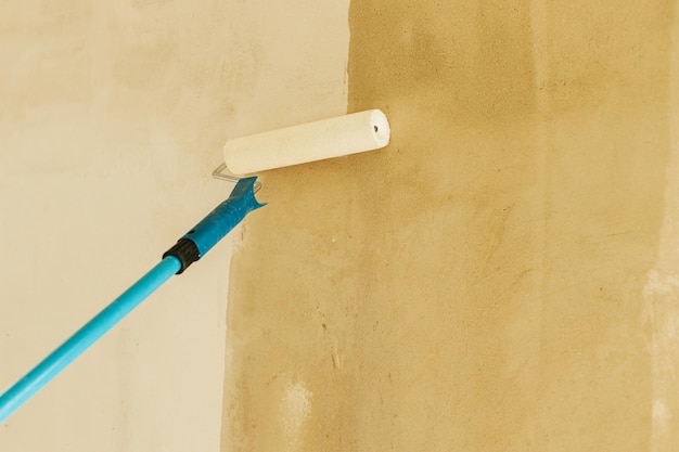 Foto pareti di adescamento dei lavoratori in un nuovo edificio spazzola a rullo con pareti in intonaco di copertura primaria costruzione di un concetto di ristrutturazione di case e abitazioni