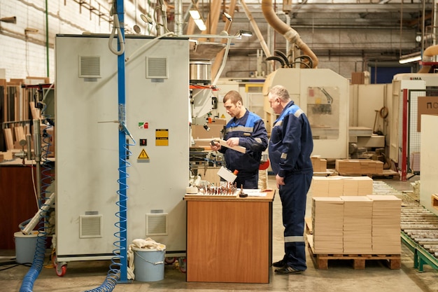 Photo a worker processes furniture blanks on a machine tool in a factory. industrial production of furniture.