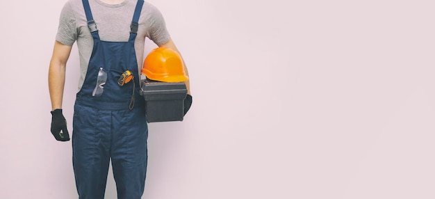 The worker in professional uniform with toolbox in hand on the gray background