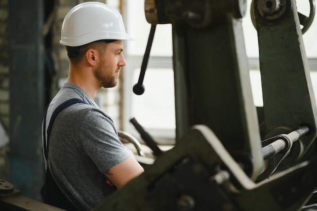 Worker in protective clothing in factory using machine