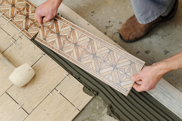 Photo worker putting tiles on the floor.