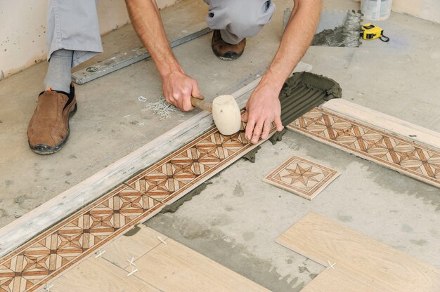 Photo worker putting tiles on the floor.