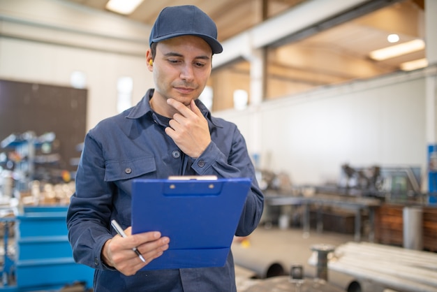 Worker reading a document in big industrial facility