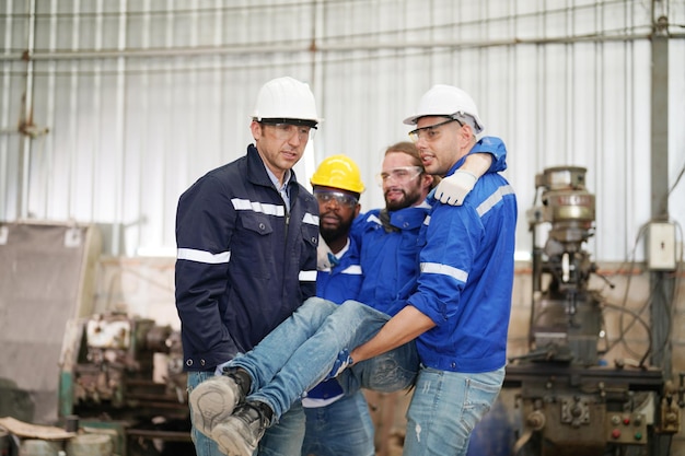 Photo worker receiving industrial injury in factory and colleague helping him while injured on leg