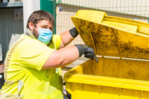 Worker in a recycling factory or clean point and garbage with a face mask and with security protections. Operator cleaning and ordering the installation