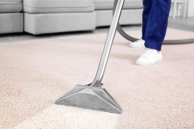 Worker removing dirt from carpet indoors closeup Cleaning service