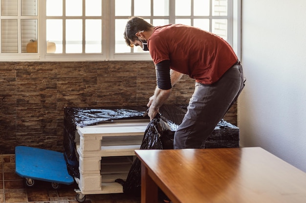 Worker removing plastic wrap from a piece of furniture in a\
moving operation