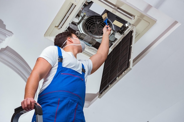 Worker repairing ceiling air conditioning unit