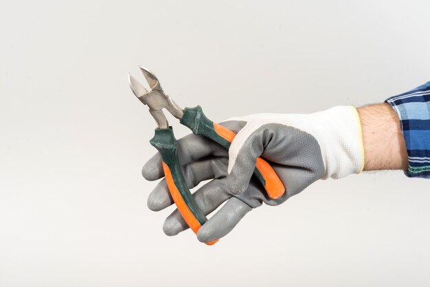 Worker repairing holding construction nippers in hand on white