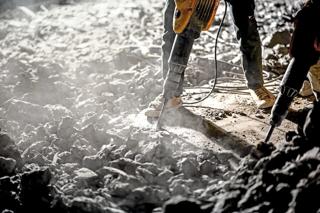 Operaio repaworker che ripara i lavori con il martello pneumatico all'anello notturno funziona con il martello pneumatico