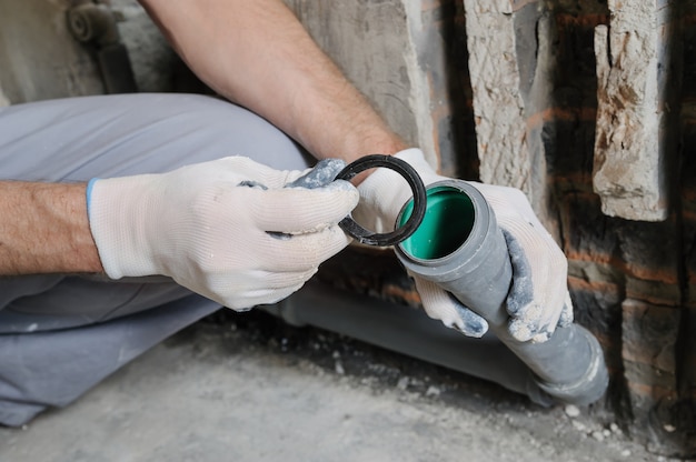 Foto le mani del lavoratore stanno installando tubi per fognatura.