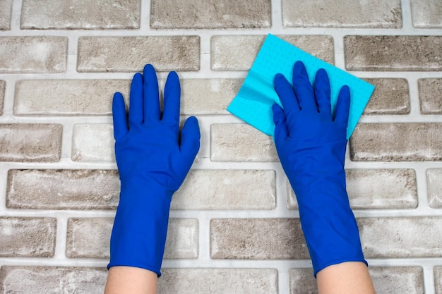 Worker's hands in rubber protective gloves with a rag wiping the surface of a table or wall in a room bathroom kitchen the concept of cleanliness