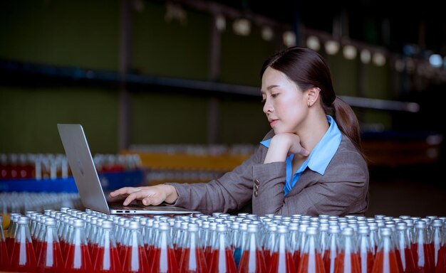 Photo worker of science in bottle beverage factory wearing safety uniform face mask discussion and working to check quality of drink basil seed produce on conveyer before distribution to marke