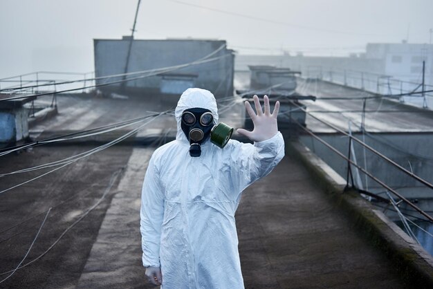 Worker scientist wearing protective coverall and gas mask doing ecological tests on the roof