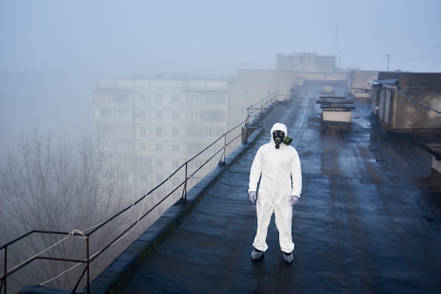 Worker scientist wearing protective coverall and gas mask doing ecological tests on the roof